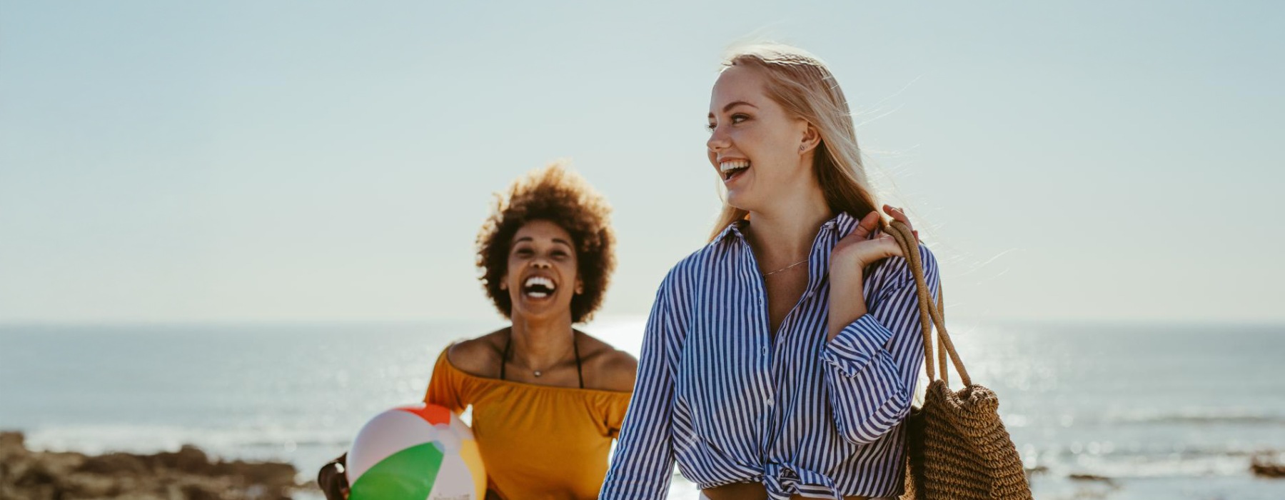 two woman laughing at the beach