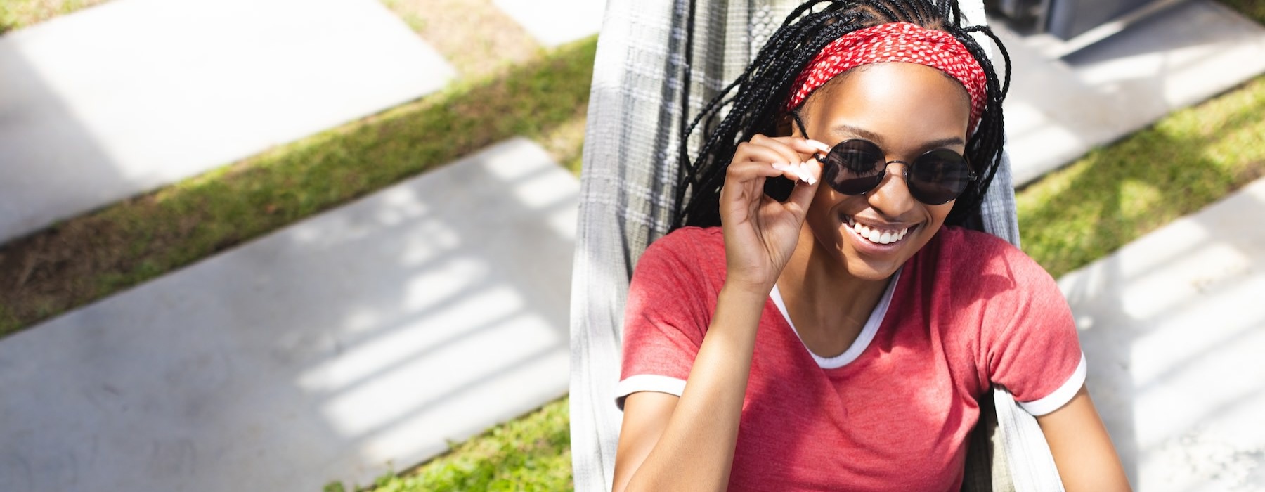 a girl sitting outside wearing a red shirt and sun glasses